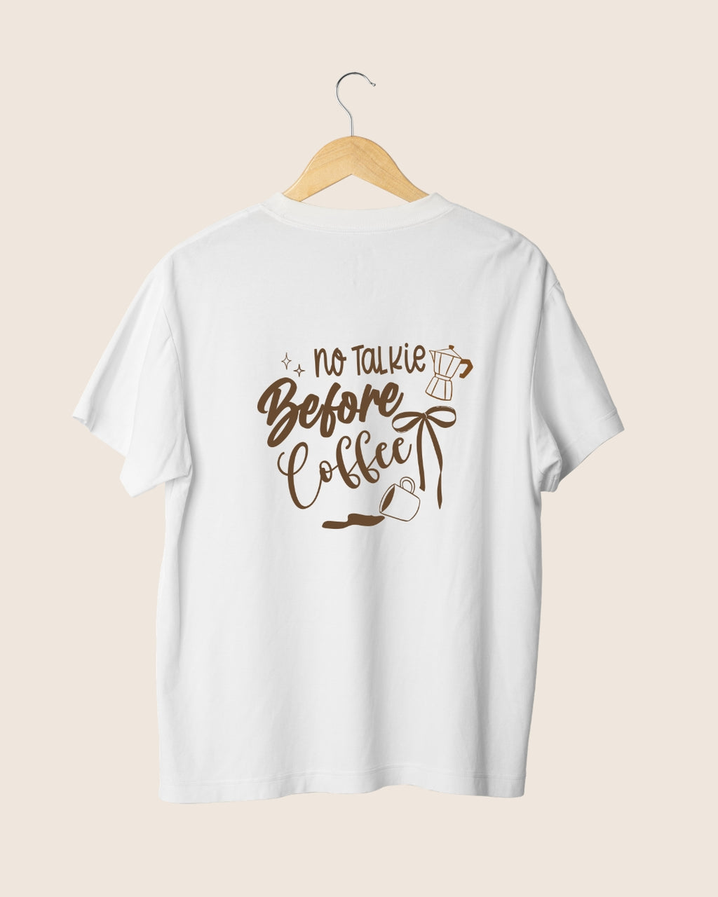 Diseño en la espalda de la camiseta blanca Before Coffee de JR.Ilustracions, con la tipografía no talkie, una taza de café derramada y una cafetera moka en color marrón.