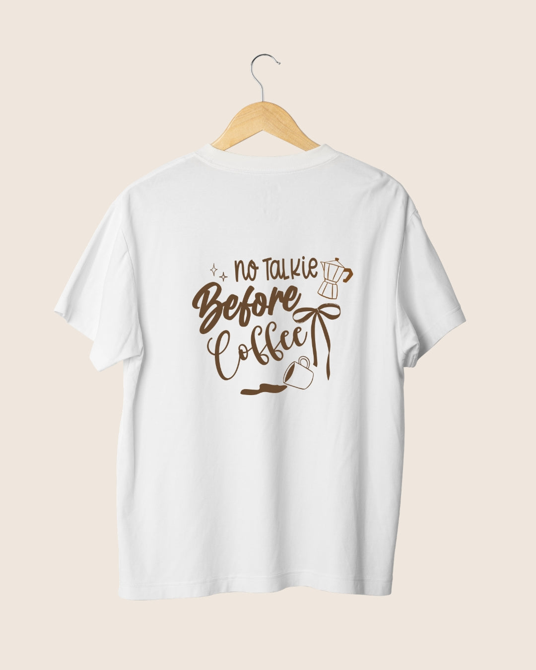 Diseño en la espalda de la camiseta blanca Before Coffee de JR.Ilustracions, con la tipografía no talkie, una taza de café derramada y una cafetera moka en color marrón.