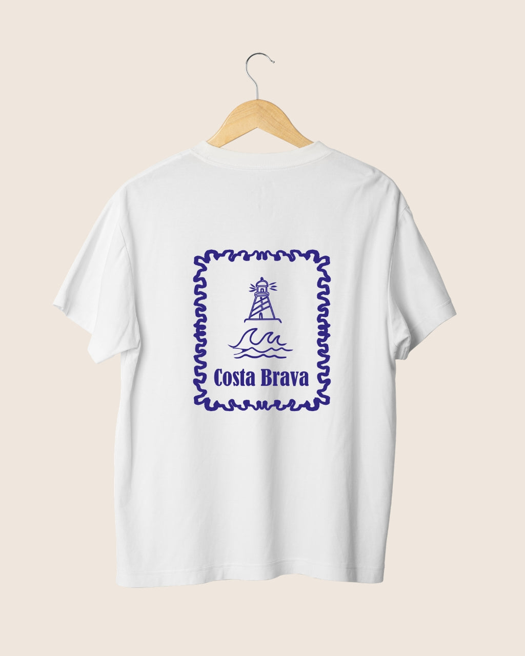 Ilustración en la espalda de la camiseta blanca Costa Brava de JR.Ilustracions, con un diseño en formato sello postal que muestra un faro sobre las olas del mar Mediterráneo.