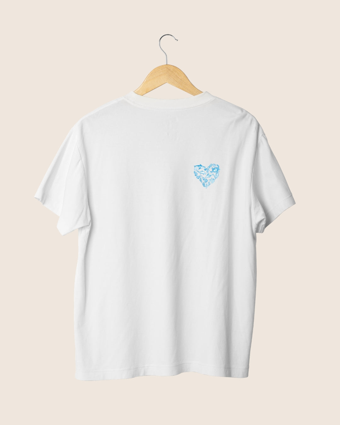 Detalle en el pecho de la camiseta blanca unisex Salty Moms, mostrando un pequeño icono en forma de corazón azul compuesto por elementos marinos.