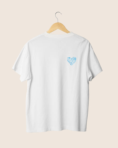 Detalle en el pecho de la camiseta blanca unisex Salty Moms, mostrando un pequeño icono en forma de corazón azul compuesto por elementos marinos.