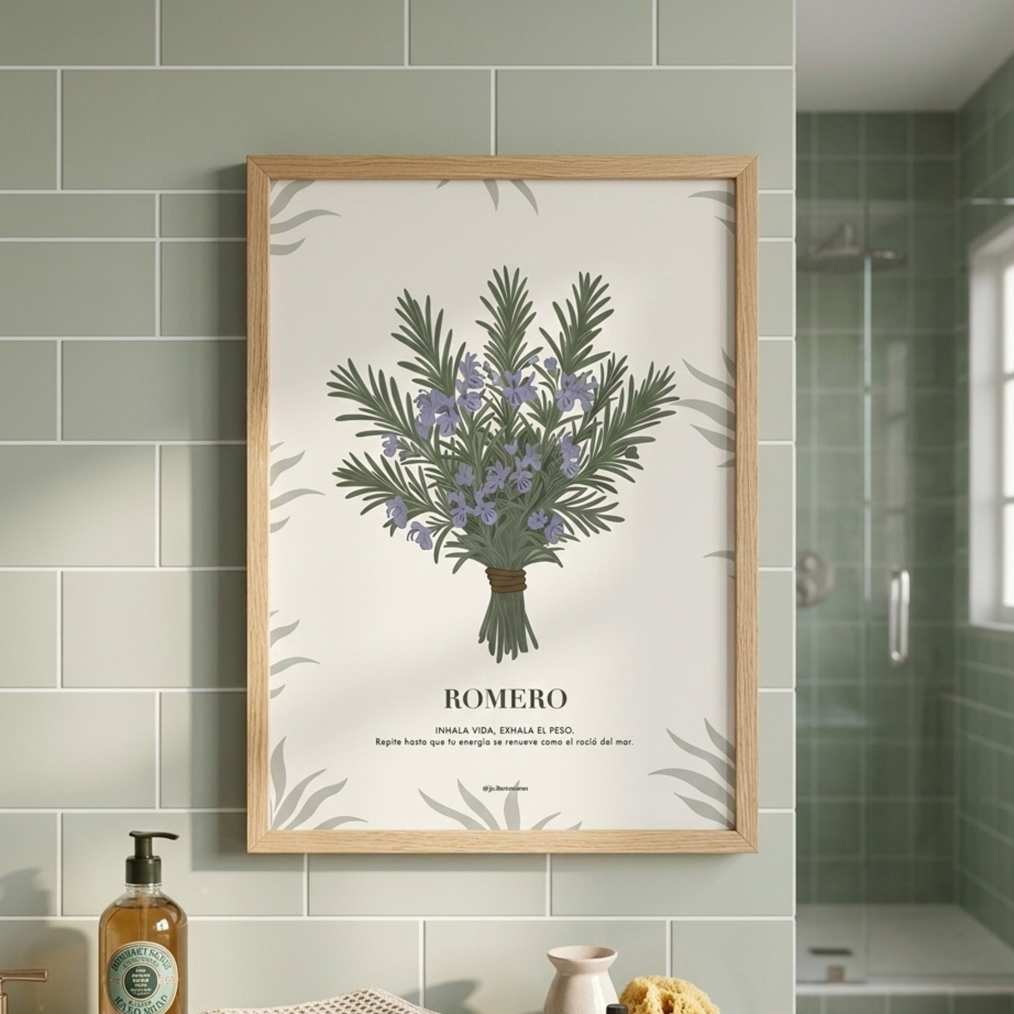Cuadro botánico de romero con marco de madera clara en pared de baño con azulejos verde salvia.