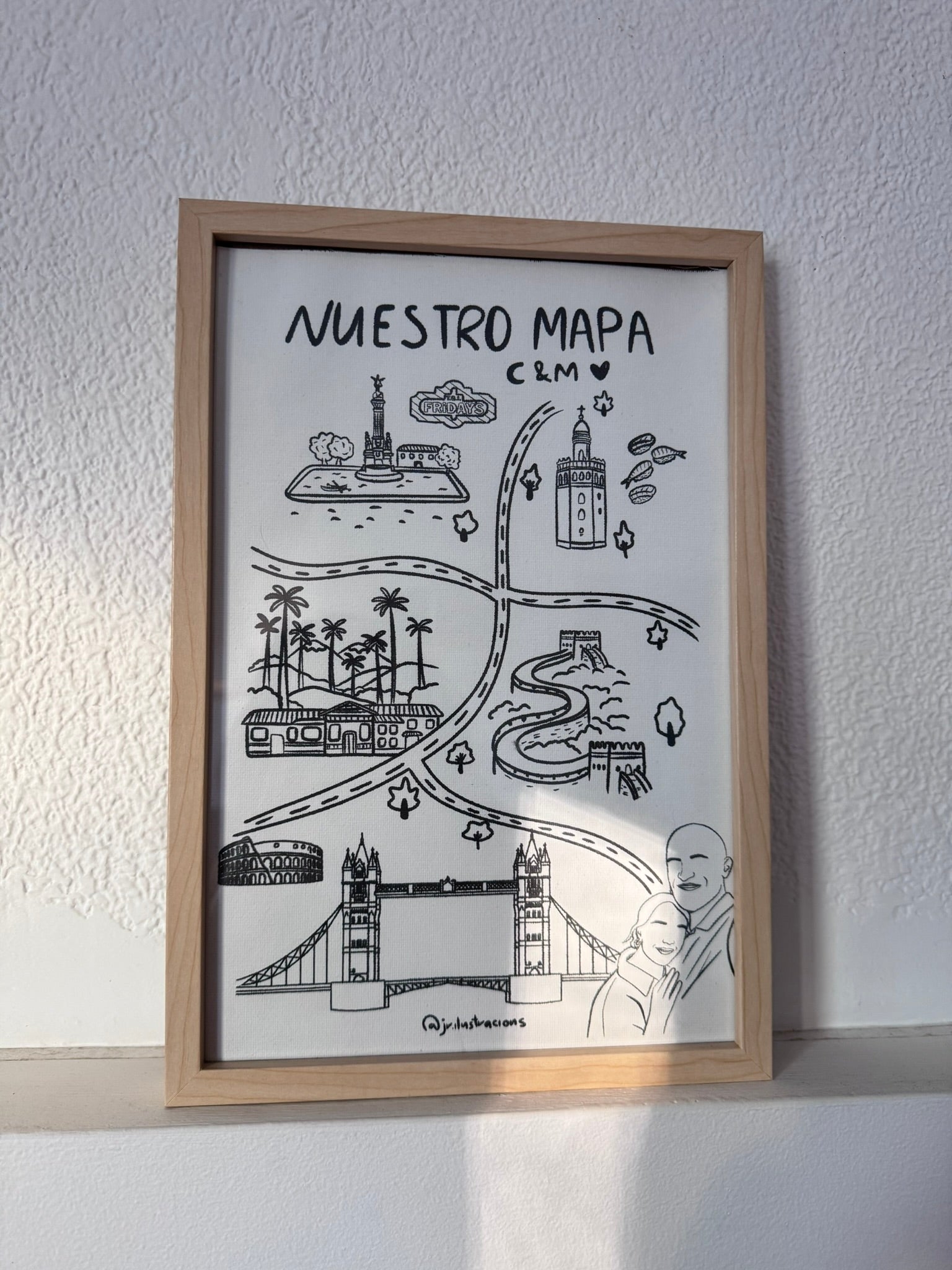 Cuadro de mapa personalizado con ilustraciones de la historia de amor de una pareja enmarcado en madera clara.