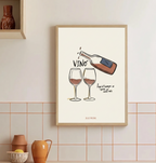 Cuadro minimalista de vino con marco de madera clara colgado sobre azulejos rosa pastel de cocina o salón.