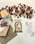 Invitaciones de boda personalizadas con ilustración de pareja bajo arco de flores y sobre kraft.