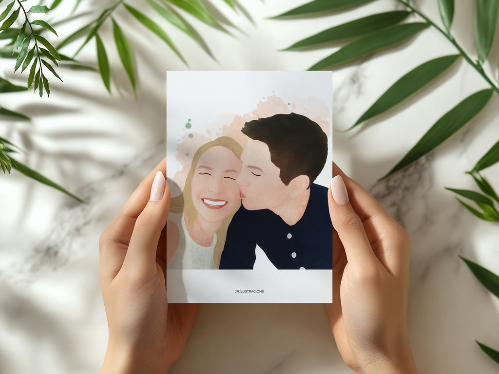 Manos sosteniendo un Mini Recuerdo Ilustrado de 10x15 cm con el retrato de una pareja besándose, sobre fondo de mármol con hojas verdes.