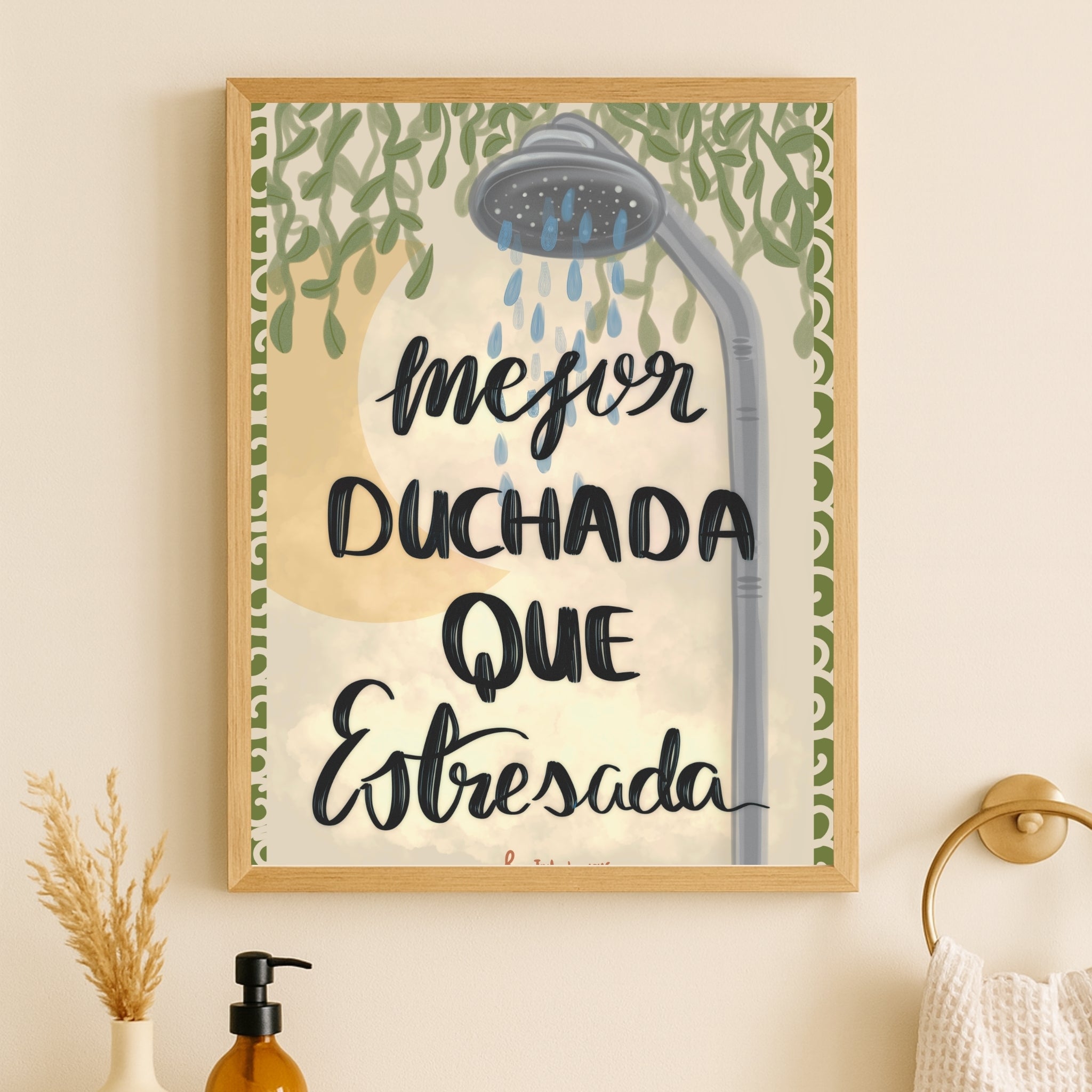 Póster con frase de humor para baño colgado junto a accesorios dorados y toallero de pared.